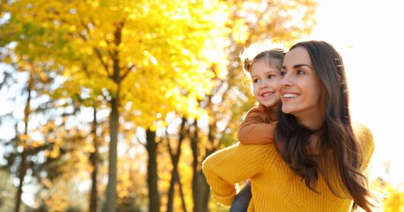 Happy woman with little daughter in sunny park. Autumn walk