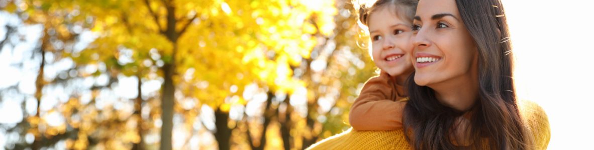 Happy woman with little daughter in sunny park. Autumn walk