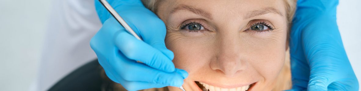 Close-up of pretty patient is having teeth examined by dentist in cabinet